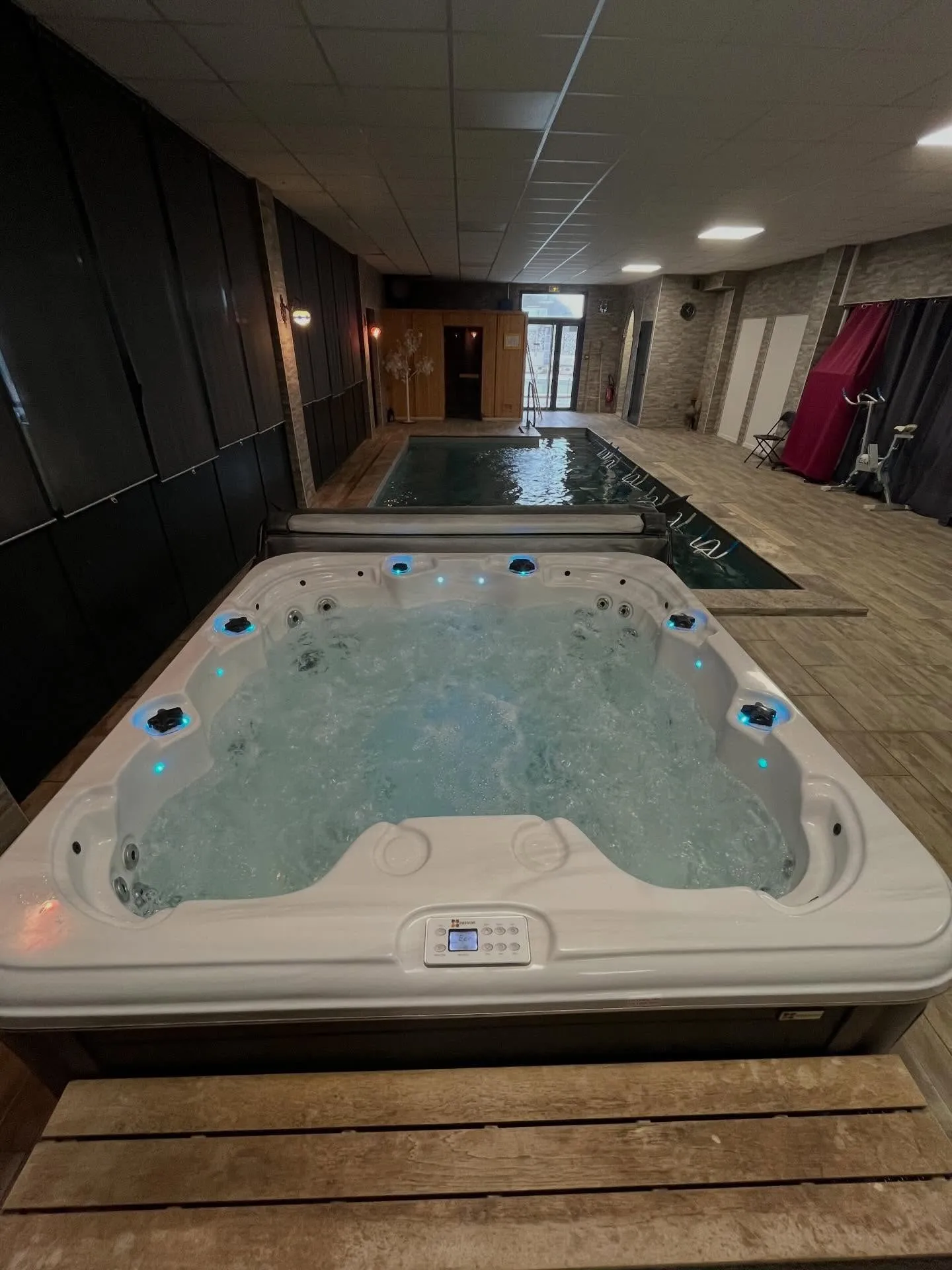 Jacuzzi intérieur aux lumières bleues devant le bassin